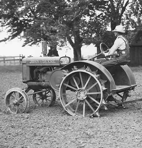 Storico trattore multiuso "GP" John Deere che traina la zappatrice rotativa n. 7 John Deere nel campo