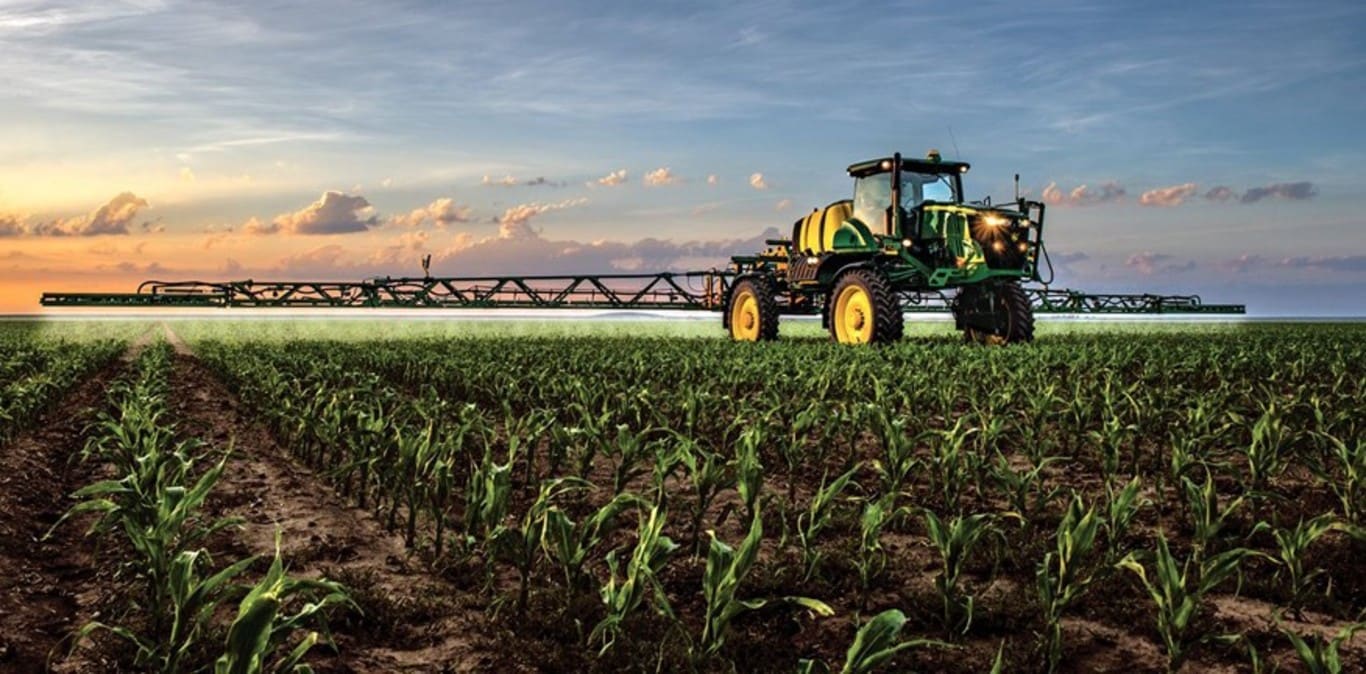 Irroratrice John Deere al lavoro in un campo di mais con tramonto sullo sfondo