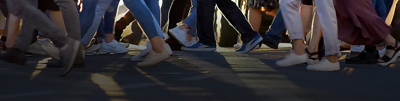 Attraversamento pedonale cittadino in cui dozzine di persone camminano in direzioni opposte mentre attraversano la strada