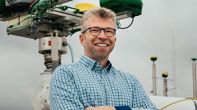 Georg Kormann in piedi accanto a un braccio robotico.