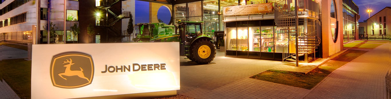 Vista anteriore della sede centrale John Deere con il laghetto e i salici in primo piano