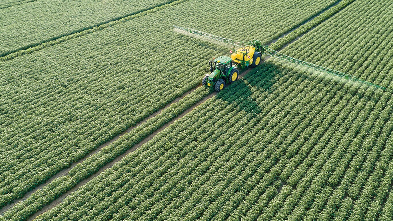 Trattore John Deere Serie 6M con irroratrice trainata M700 al traino in un campo di patate